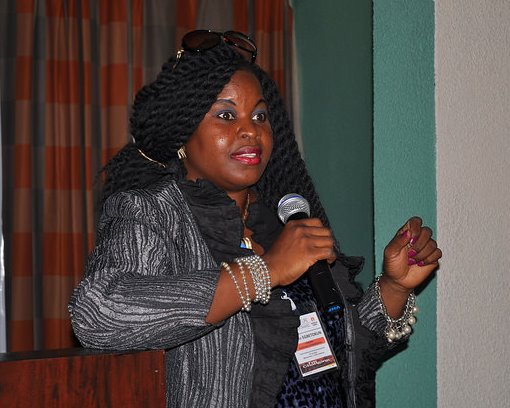 Olutope Olatilewa E. (Lady Topsie) speaking on stage with a microphone
